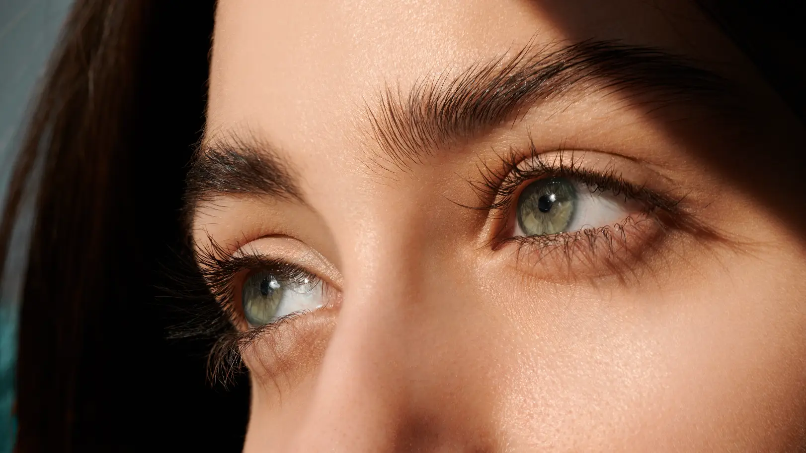 Close-up of green eyes with defined upper eyelashes and naturally shaped eyebrows.